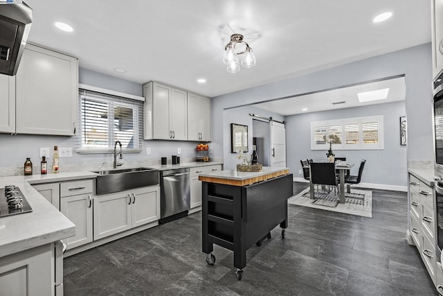 kitchen with sink, wooden counters, dishwasher, a barn door, and white cabinets