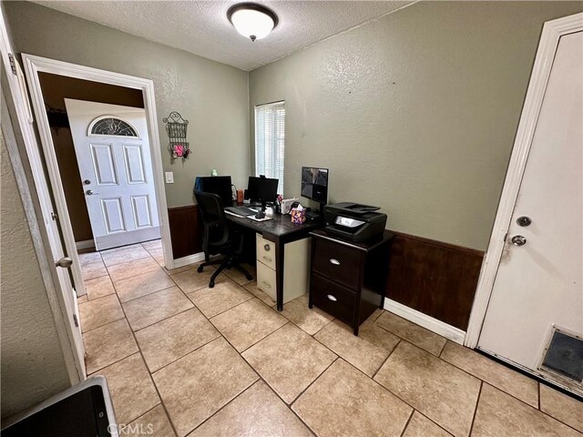 office area with light tile patterned flooring, wooden walls, and a textured ceiling