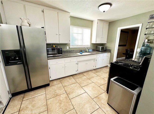 kitchen featuring sink, white cabinetry, stainless steel fridge with ice dispenser, a textured ceiling, and light tile patterned floors