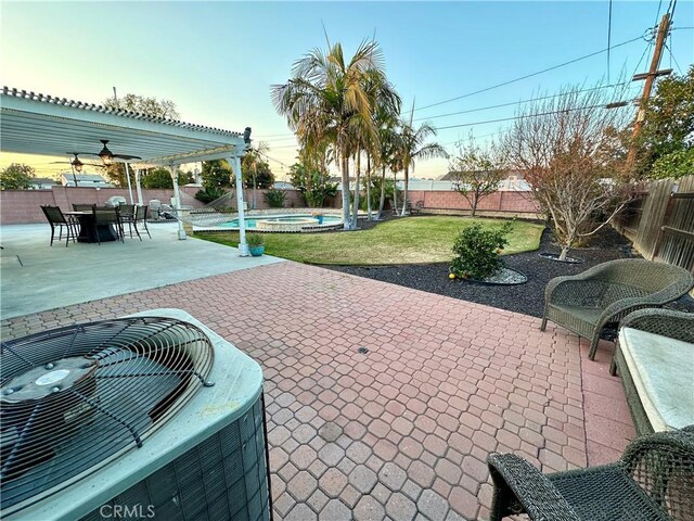 patio terrace at dusk featuring a lawn, ceiling fan, and central air condition unit