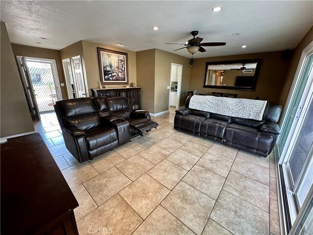 living room featuring light tile patterned floors, a textured ceiling, and ceiling fan