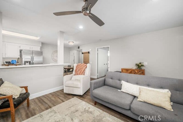 living room with dark hardwood / wood-style flooring and ceiling fan