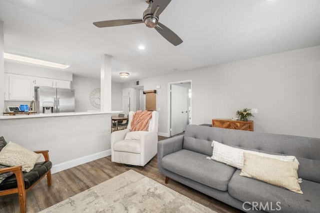 living area with dark wood-style flooring, ceiling fan, and baseboards