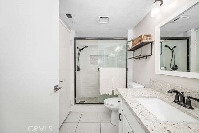 bathroom with an enclosed shower, vanity, tile patterned floors, and toilet