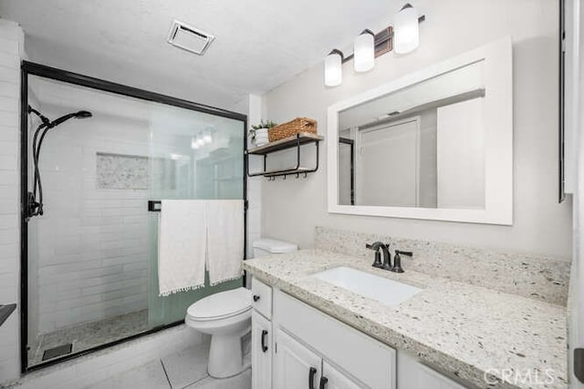 bathroom with visible vents, toilet, a shower stall, vanity, and tile patterned flooring