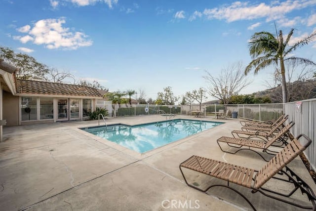 community pool with a patio area and fence