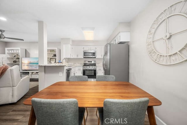 dining space featuring a ceiling fan, dark wood-style flooring, and baseboards