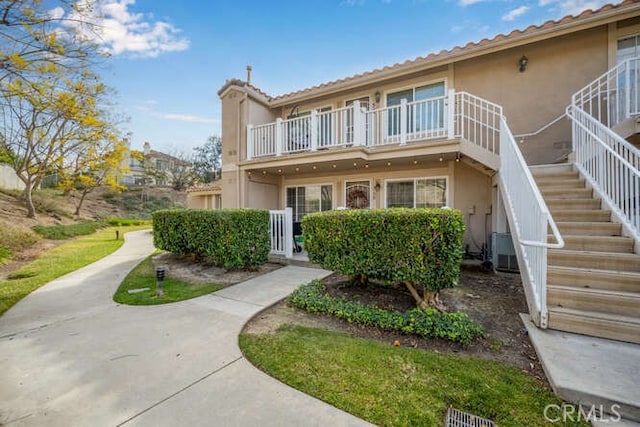 view of front of property featuring a balcony, stairs, and stucco siding