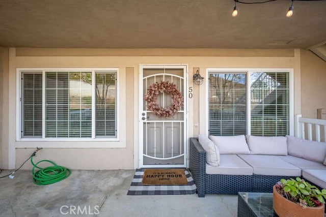 property entrance featuring an outdoor hangout area, a patio, and stucco siding