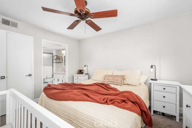 bedroom with ensuite bathroom, carpet floors, and ceiling fan