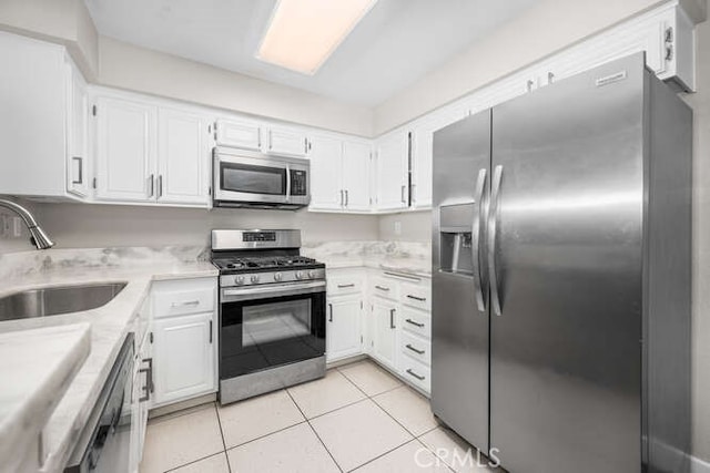 kitchen with light tile patterned floors, a sink, white cabinets, light countertops, and appliances with stainless steel finishes