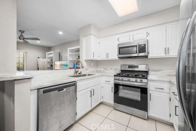 kitchen featuring a peninsula, appliances with stainless steel finishes, a sink, and white cabinetry