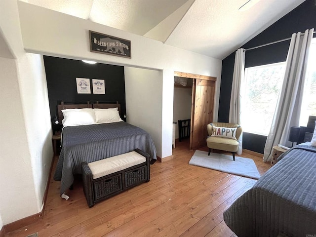 bedroom with lofted ceiling, a textured ceiling, and light wood-type flooring