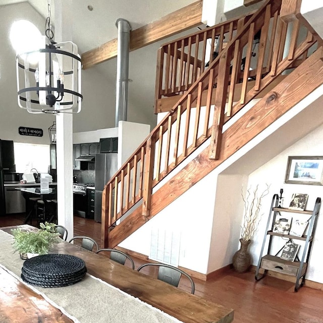 staircase with an inviting chandelier, hardwood / wood-style flooring, and a high ceiling