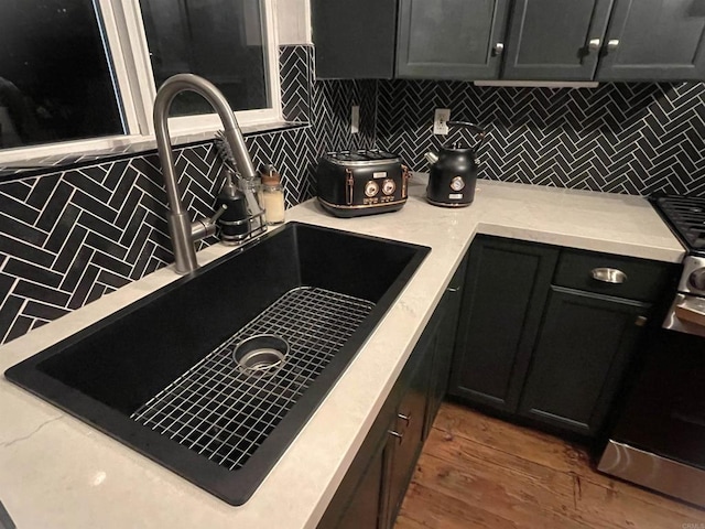 kitchen featuring stove, sink, backsplash, and hardwood / wood-style floors