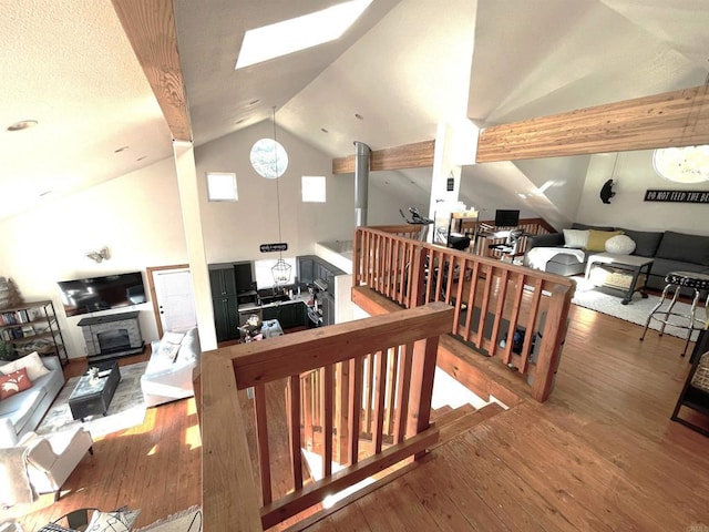 interior space featuring a skylight, wood-type flooring, high vaulted ceiling, and a wood stove