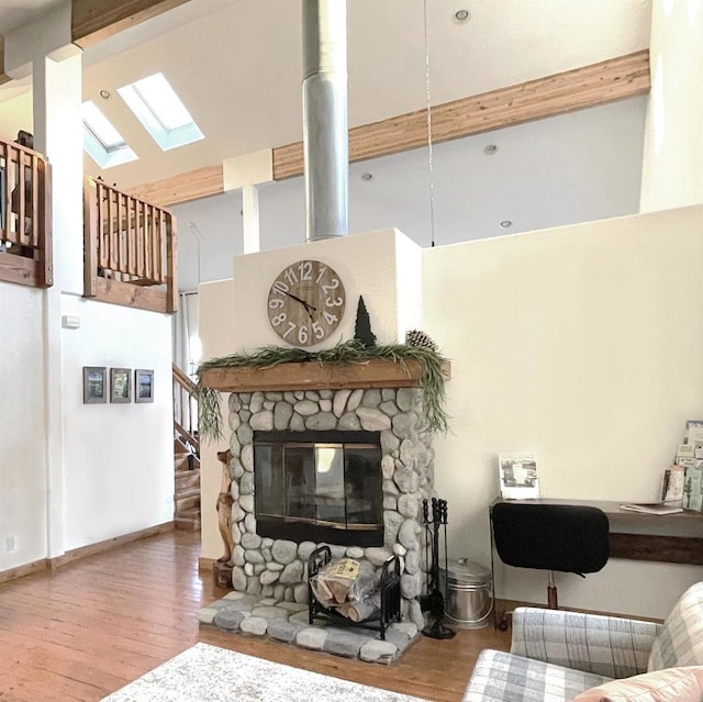 living area with a skylight, baseboards, wood finished floors, stairs, and high vaulted ceiling