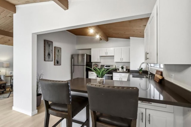 kitchen with white cabinetry, sink, vaulted ceiling with beams, and stainless steel refrigerator