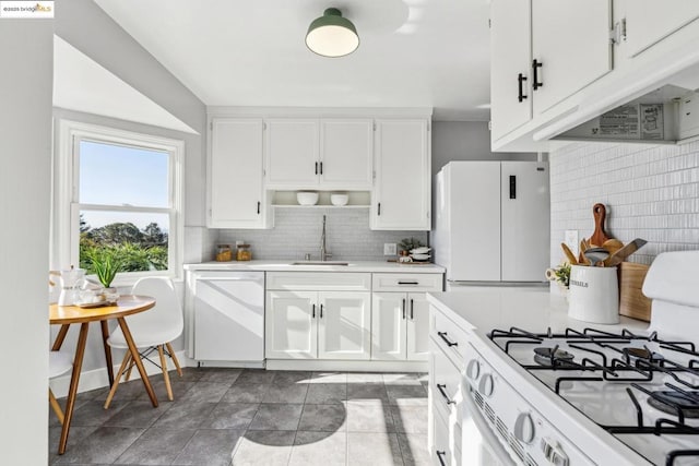 kitchen with tasteful backsplash, sink, white cabinets, and white appliances