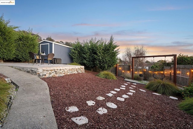 yard at dusk featuring a storage shed and a patio