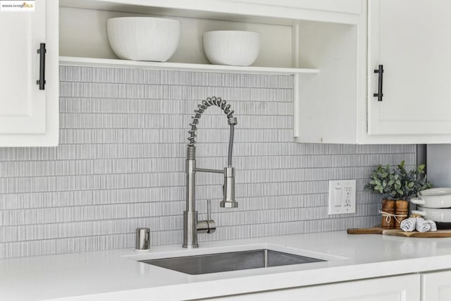 kitchen featuring electric panel, sink, white cabinets, and decorative backsplash