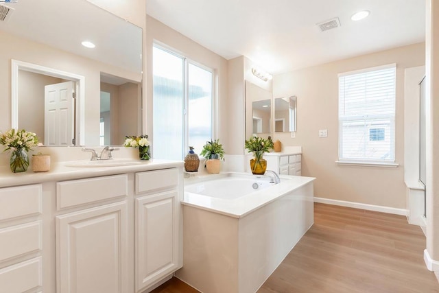 bathroom featuring hardwood / wood-style flooring, plenty of natural light, a bath, and vanity