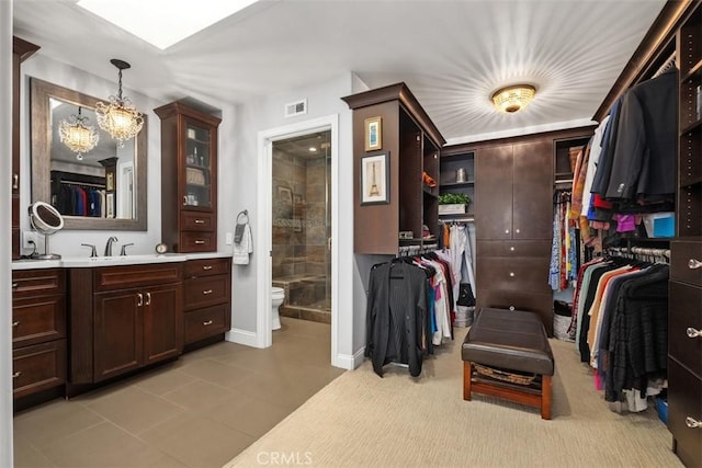 spacious closet featuring sink and a notable chandelier