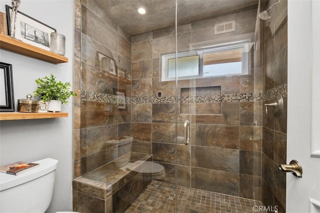 bathroom with a shower with door and toilet