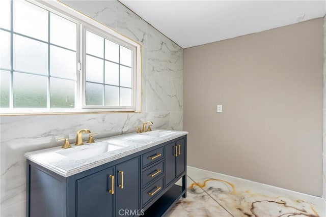 full bathroom featuring a sink, baseboards, and double vanity