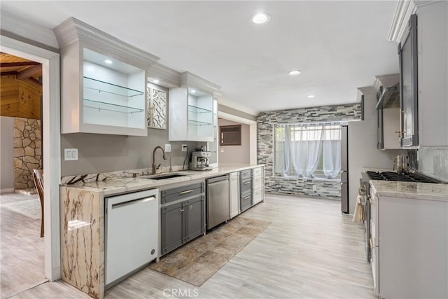 kitchen with stainless steel dishwasher, dishwasher, a sink, light wood finished floors, and gray cabinetry