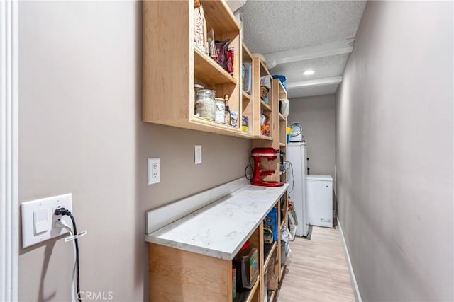 laundry area featuring baseboards, recessed lighting, light wood-style flooring, a textured ceiling, and laundry area