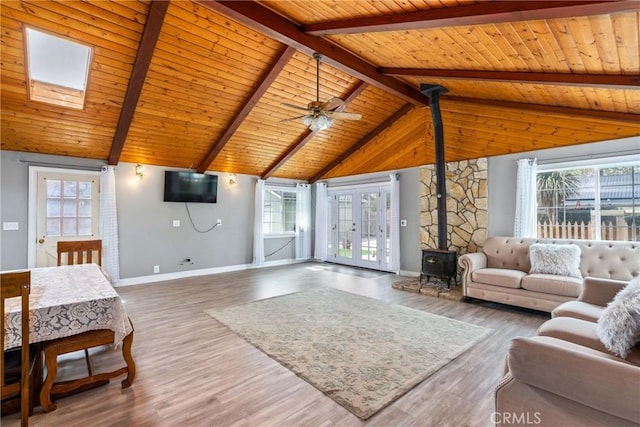 living area featuring lofted ceiling with beams, wood ceiling, wood finished floors, and a wood stove