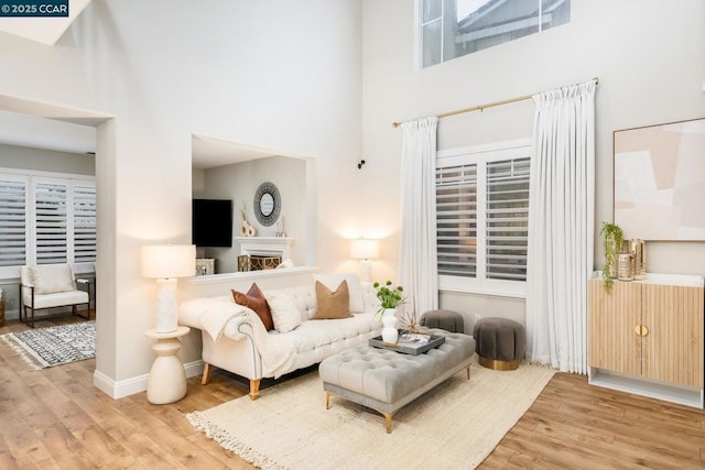 living room with a towering ceiling and light wood-type flooring