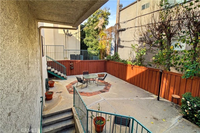 view of patio with stairs and fence