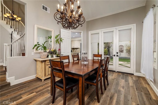 dining space with a notable chandelier, crown molding, dark hardwood / wood-style floors, and french doors