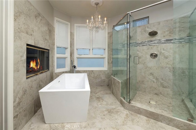 bathroom with a premium fireplace, a chandelier, tile walls, and plus walk in shower