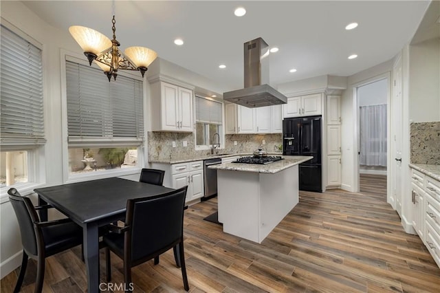 kitchen with a center island, island range hood, light stone countertops, decorative light fixtures, and black refrigerator with ice dispenser