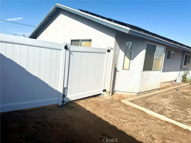 view of side of property with fence and stucco siding
