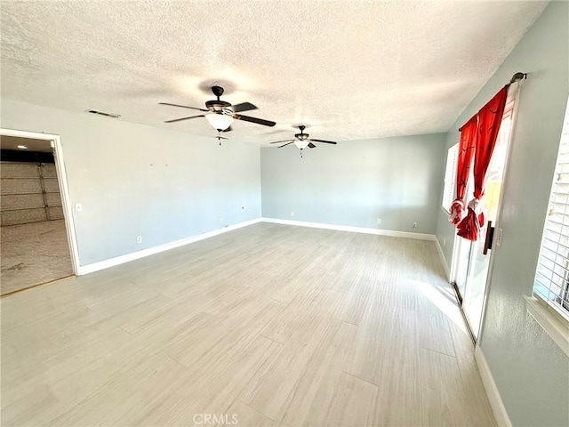 empty room with ceiling fan, light hardwood / wood-style floors, and a textured ceiling