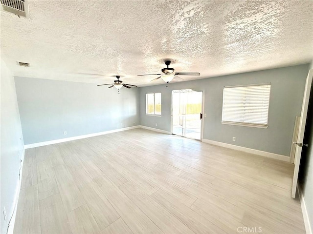 unfurnished room featuring light wood finished floors, visible vents, a ceiling fan, and baseboards