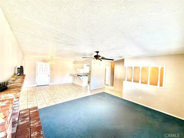 unfurnished living room featuring light carpet, a ceiling fan, a textured ceiling, light tile patterned flooring, and baseboards