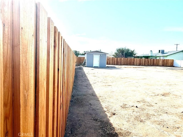 view of yard featuring a storage unit, an outbuilding, and a fenced backyard