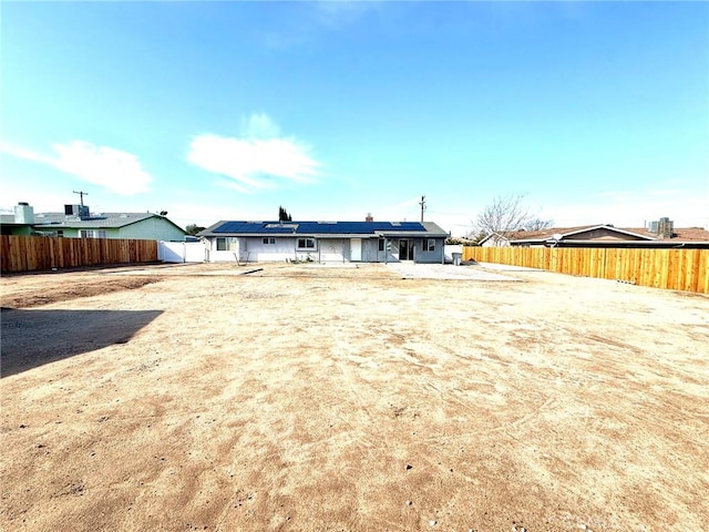 back of property featuring solar panels and a fenced backyard
