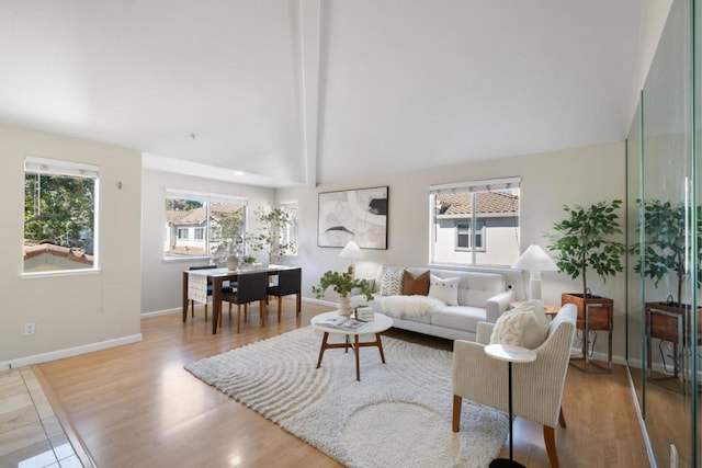 living room with vaulted ceiling with beams and light wood-type flooring