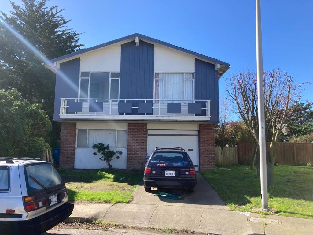 view of front facade featuring a balcony, a garage, and a front lawn