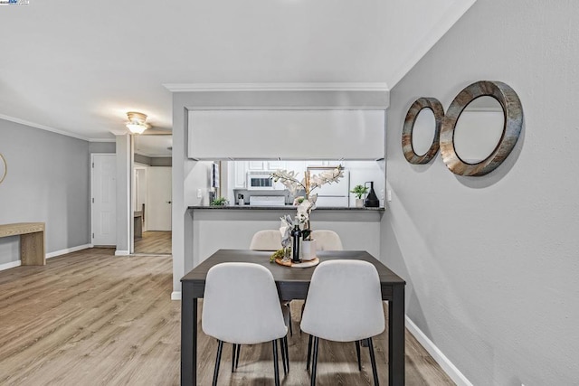 dining space with ornamental molding and light hardwood / wood-style floors