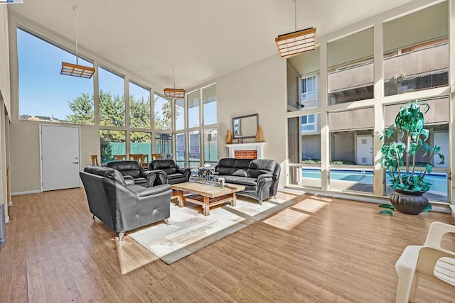 living room with a towering ceiling, light hardwood / wood-style floors, and a wall of windows