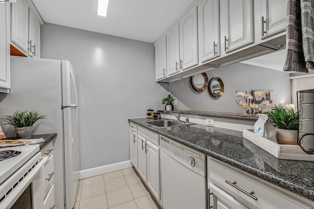 kitchen featuring sink, dark stone countertops, white cabinets, light tile patterned floors, and white appliances