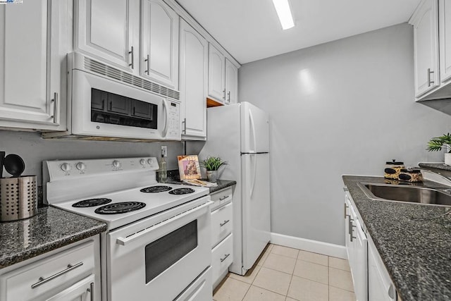 kitchen with white cabinetry, sink, dark stone countertops, light tile patterned floors, and white appliances