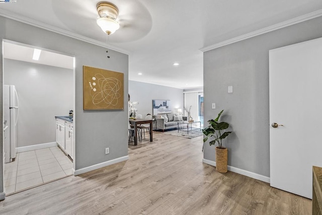 interior space with crown molding, white fridge, white cabinets, and light wood-type flooring